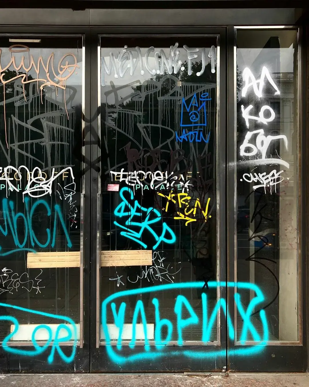 Vidrio de escaparate cubierto de graffiti — el tipo de daño que absorbe la película antigraffiti
