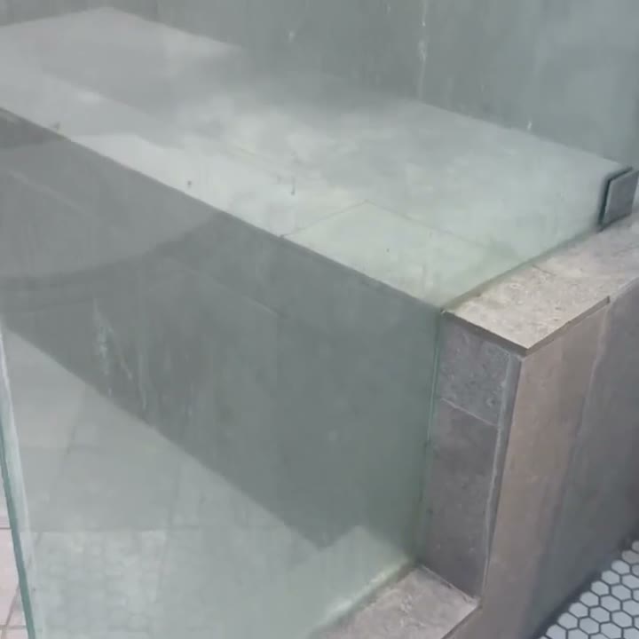 Manchas de agua dura en el vidrio de la regadera — neblina blanca de minerales cubriendo el panel antes de la restauración